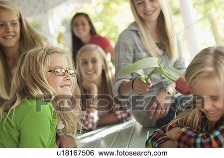 USA, Utah, family portrait of sisters (6-7, 8-9, 12-13, 14-15, 16-17) at table playing with flower View Large Photo Image Stock Photograph - USA, Utah, family portrait of sisters (6-7, 8-9, 12-13, 14-15, 16-17) at table playing with flower. Fotosearch