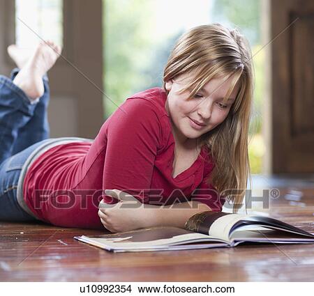 Picture - USA, Utah, Girl (10-11) reading book on floor in home. Fotosearch