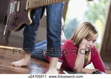 USA, Utah, Girl (10-11) reading magazine while another girl (6-7) playing guitar View Large Photo Image Stock Image - USA, Utah, Girl (10-11) reading magazine while another girl (6-7) playing guitar. Fotosearch