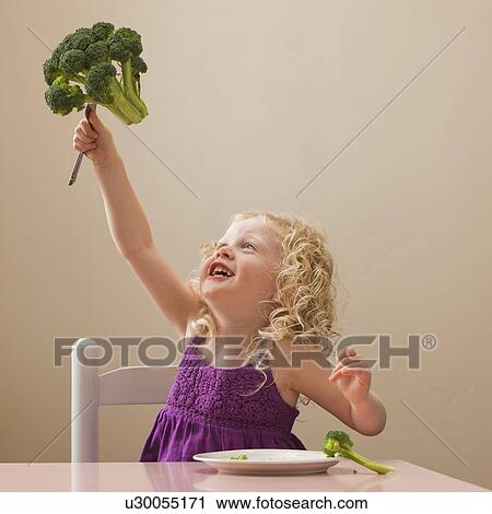 Stock Image - USA, Utah, Lehi, girl (2-3) holding broccoli. Fotosearch