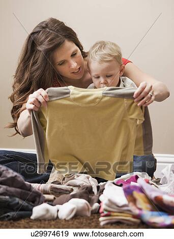 Stock Photo - USA, Utah, Lehi, mother and son (18-23 months) folding laundry. Fotosearch