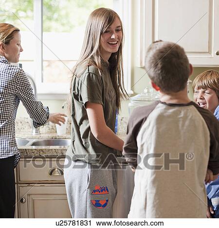 Stock Image - USA, Utah, Mother with three kids (8-9, 10-11, 14-15) in kitchen. Fotosearch