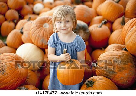 Stock Image - USA, Utah, Orem, portrait of girl (2-3) holding pumpkin. Fotosearch