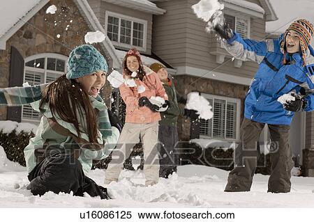 Stock Photography - USA, Utah, Provo, Boys (10-11, 12-13) and girls (10-11, 16-17) having snow ball fight in front of house. Fotosearch