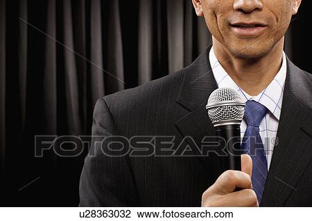 USA, Utah, Provo, Close-up of businessman with microphone standing in front of black curtain, mid section View Large Photo Image Stock Image - USA, Utah, Provo, Close-up of businessman with microphone standing in front of black curtain, mid section. Fotosearch