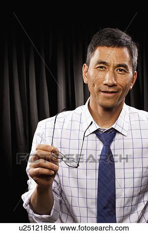 Picture - USA, Utah, Provo, Portrait of businessman standing in front of black curtain. Fotosearch