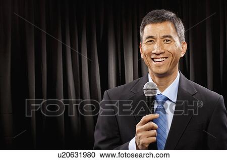 USA, Utah, Provo, Portrait of businessman with microphone standing in front of black curtain View Large Photo Image Stock Image - USA, Utah, Provo, Portrait of businessman with microphone standing in front of black curtain. Fotosearch