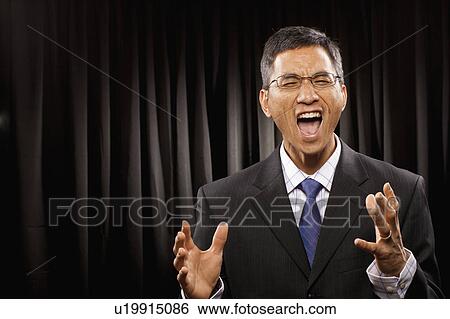 Stock Photograph - USA, Utah, Provo, Portrait of businessman having speech in front of black curtain. Fotosearch