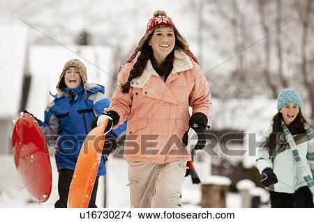Picture - USA, Utah, Provo, Teenage (16-17) girl running with sledge, boys and girls (10-11, 12-13) in background. Fotosearch