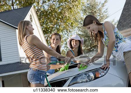 Stock Image - USA, Utah, Provo, Teenage girls (16-17) and young women watching car. Fotosearch