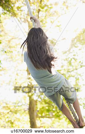 Stock Photo - USA, Utah, rear view of girl (10-11) hanging on rope. Fotosearch