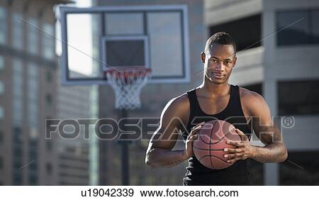 Stock Photo - USA, Utah, Salt Lake City, basketball player holding basketball. Fotosearch