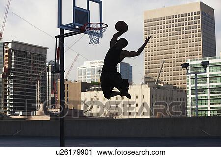 Stock Image - USA, Utah, Salt Lake City, Silhouette of young man playing basketball. Fotosearch