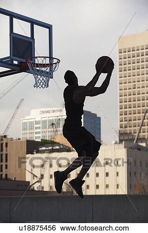 Stock Photograph - USA, Utah, Salt Lake City, Silhouette of young man playing basketball. Fotosearch