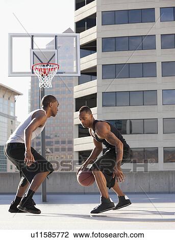 Stock Image - USA, Utah, Salt Lake City, two young men playing basketball. Fotosearch