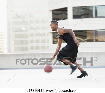 Stock Image - USA, Utah, Salt Lake City, Young man playing basketball. Fotosearch