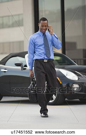 USA, Utah, Salt Lake City, Young businessman walking and talking on mobile phone View Large Photo Image Stock Image - USA, Utah, Salt Lake City, Young businessman walking and talking on mobile phone. Fotosearch
