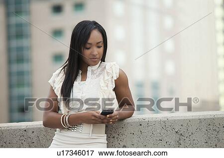 Stock Photo - USA, Utah, Salt Lake City, Young businesswoman text messaging. Fotosearch