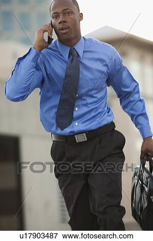 USA, Utah, Salt Lake City, Young businessman running and talking on mobile phone View Large Photo Image Stock Photo - USA, Utah, Salt Lake City, Young businessman running and talking on mobile phone. Fotosearch