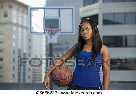 Stock Image - USA, Utah, Salt Lake City, young woman holding basketball. Fotosearch