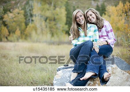 Stock Photography - USA, Utah, Sundance, Portrait of two young women sitting on boulder. Fotosearch