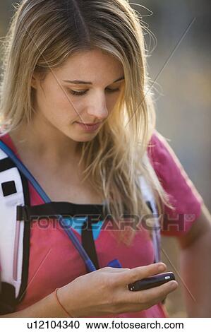 Stock Image - USA, Utah, young woman hiking in forest and talking on mobile phone. Fotosearch