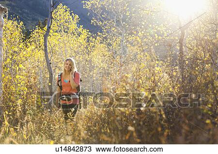 USA, Utah, young woman hiking in forest and talking on mobile phone View Large Photo Image Stock Image - USA, Utah, young woman hiking in forest and talking on mobile phone. Fotosearch