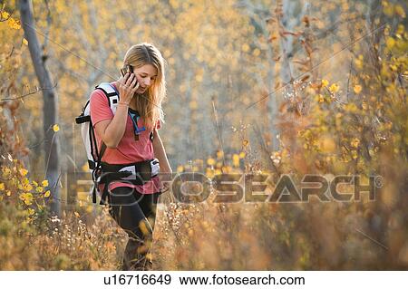 USA, Utah, young woman hiking in forest and talking on mobile phone View Large Photo Image Stock Photo - USA, Utah, young woman hiking in forest and talking on mobile phone. Fotosearch