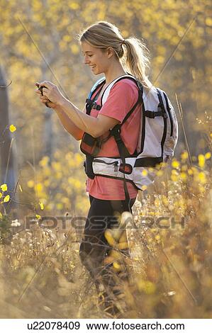Stock Photo - USA, Utah, young woman taking photograph in forest. Fotosearch