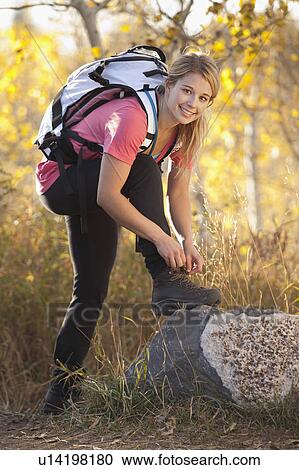 Stock Image - USA, Utah, young woman, woman tying laces in forest. Fotosearch