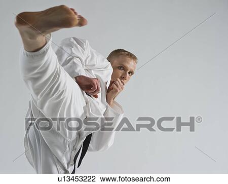 Young man performing karate kick on white background View Large Photo Image Stock Image - Young man performing karate kick on white background. Fotosearch
