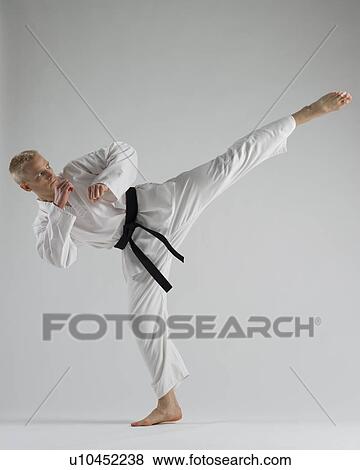 Stock Photo - Young man performing karate kick on white background. Fotosearch
