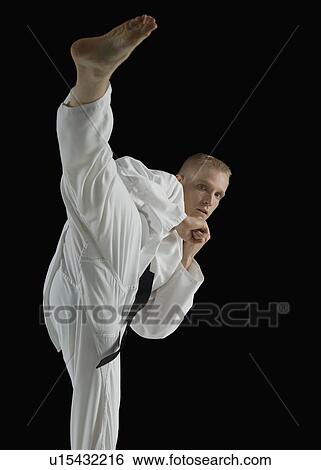 Young man performing karate kick on black background View Large Photo Image Stock Photograph - Young man performing karate kick on black background. Fotosearch