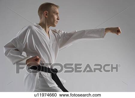 Stock Image - Young man performing karate stance on white background. Fotosearch