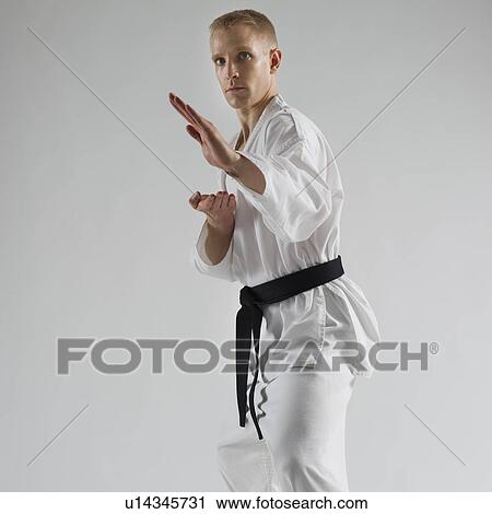 Stock Image - Young man performing karate stance on white background. Fotosearch