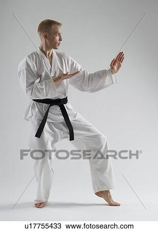 Young man performing karate stance on white background View Large Photo Image Stock Image - Young man performing karate stance on white background. Fotosearch