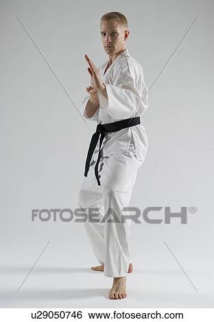 Stock Photograph - Young man performing karate stance on white background. Fotosearch