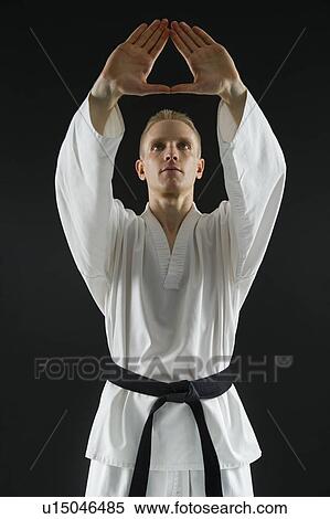 Stock Photography - Young man performing karate stance on black background. Fotosearch