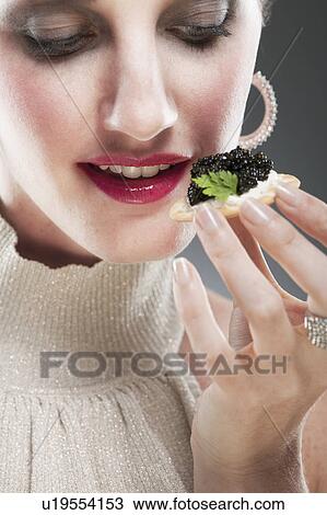 Young woman eating caviar on biscuit View Large Photo Image Stock Image - Young woman eating caviar on biscuit. Fotosearch