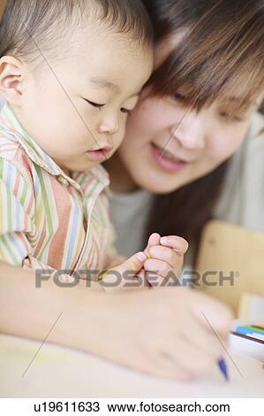 Stock Image - A boy drawing with mother. Fotosearch