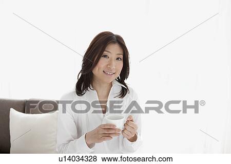 Stock Photo - A woman holding a cup. Fotosearch
