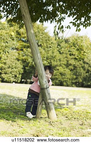 Stock Image - Baby Girl Behind Wooden Post. Fotosearch