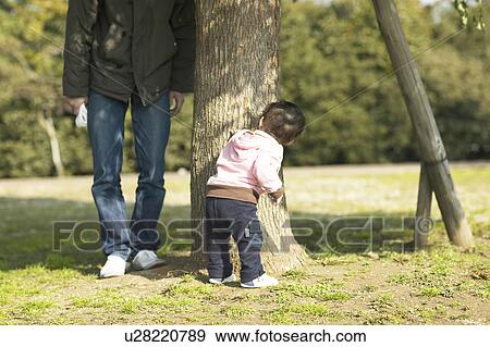 Stock Photo - Baby Hiding From Father Behind Tree. Fotosearch