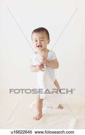 Stock Photography - Boy Standing Holding Towel Smiling. Fotosearch