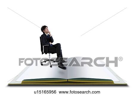 Stock Photograph - Businessman Sitting Chair Hand On Chin Open Book. Fotosearch