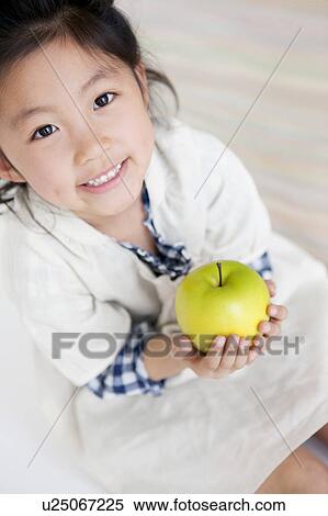 Girl holding an apple View Large Photo Image Stock Photography - Girl holding an apple. Fotosearch