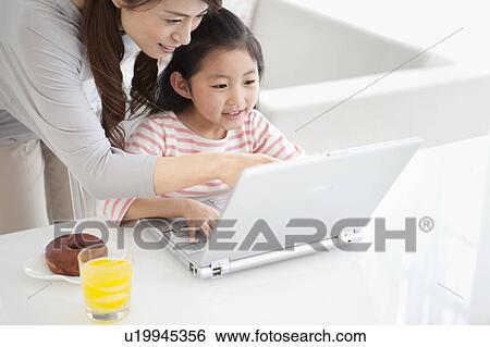 Stock Photograph - Mother and daughter using laptop. Fotosearch