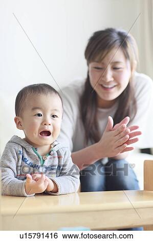 Stock Photograph - Mother Son Sitting Watching Television Clapping. Fotosearch