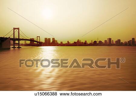 Stock Photo - Rainbow Bridge Sea Skyline Waterfront Sunset. Fotosearch