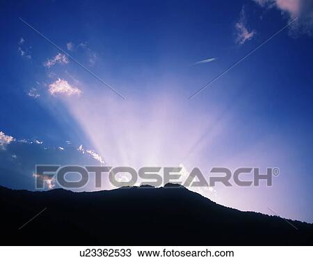 Stock Image - Sun Shining Behind Mountain. Fotosearch
